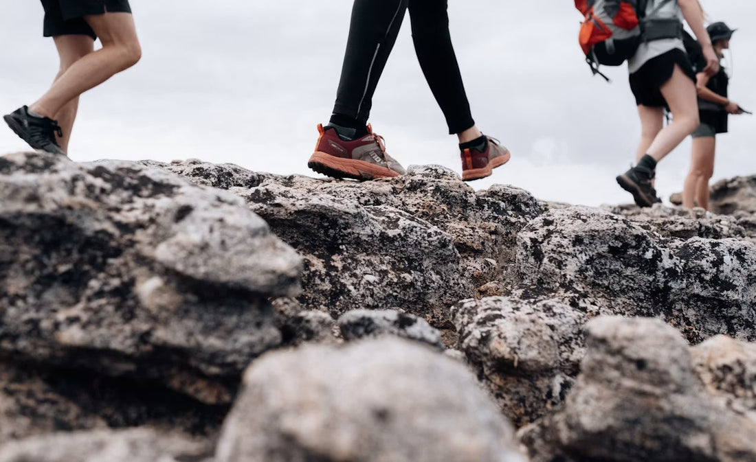 Hiking boots and trail runners side by side on a forest hiking trail